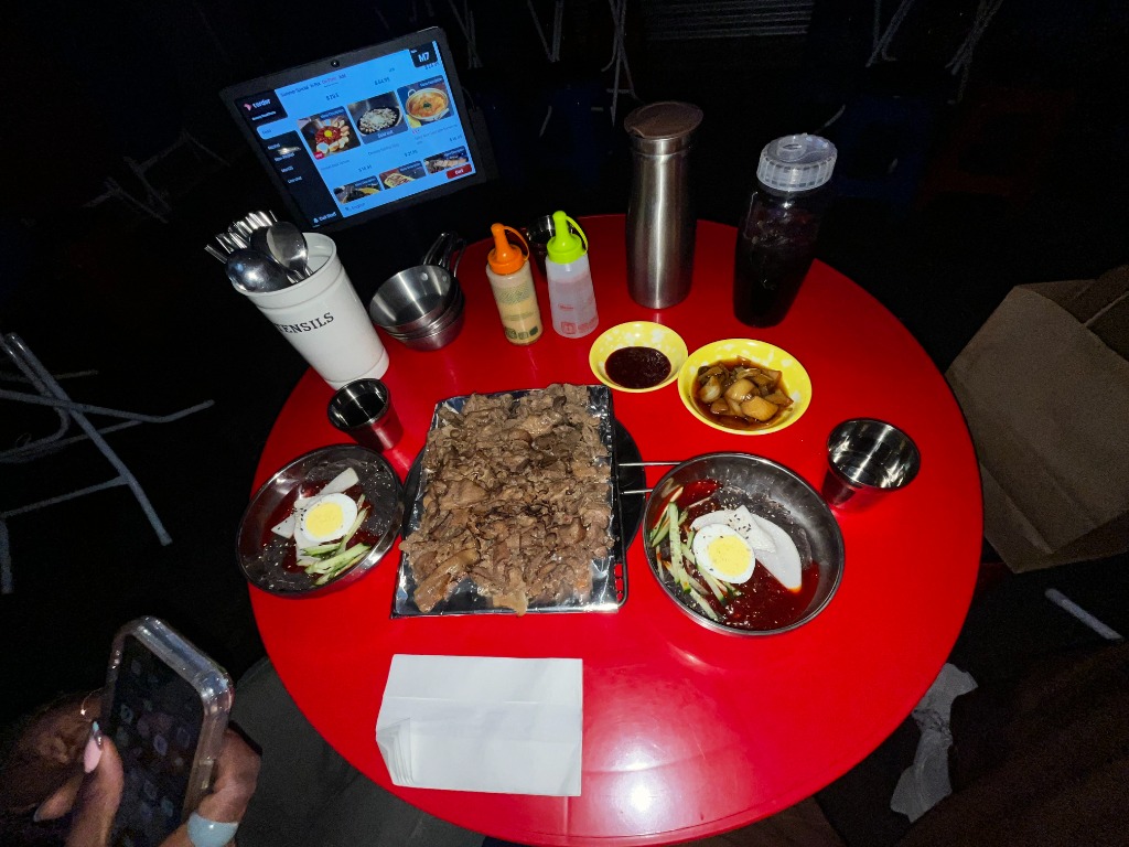 A Korean barbecue spread with cold noodles on a red table