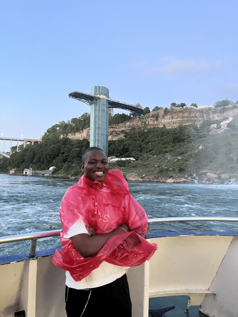 Pamimo smiling in a red rain poncho on a boat in a waterfall gorge